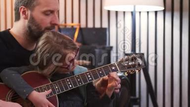 爸爸和女儿一起弹<strong>吉他</strong>。 小女孩在家和父亲一起学<strong>吉他</strong>。 前景。 <strong>吉他</strong>课